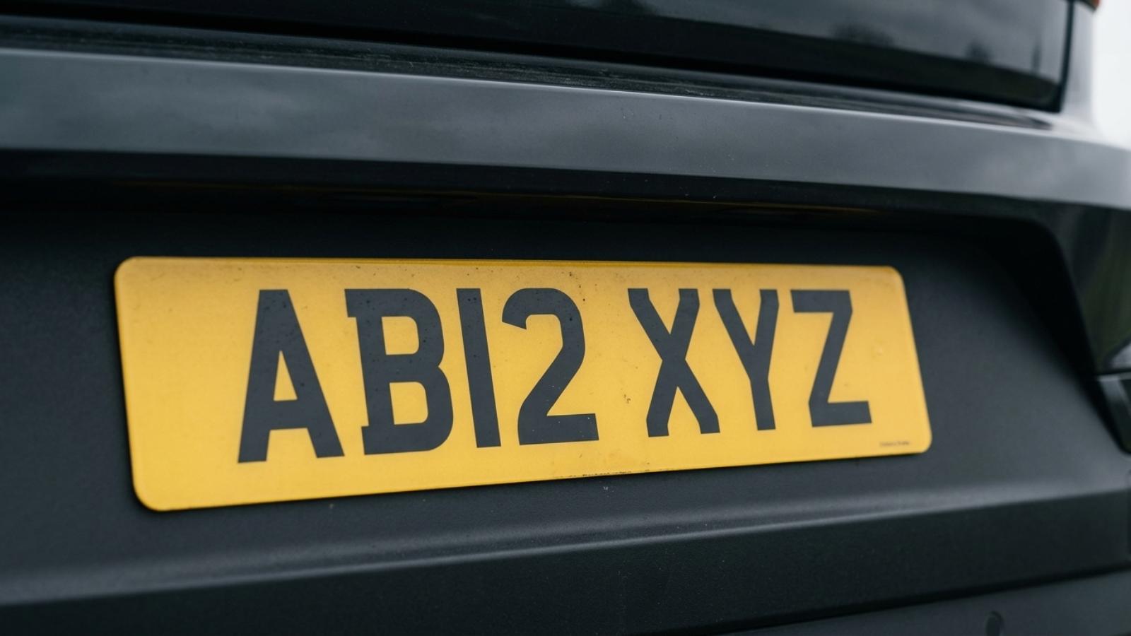 Close-up of a UK yellow rear number plate on a dark car